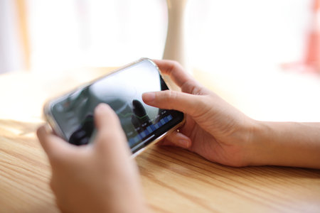 Woman hand using a smartphone for Stock exchange trading online in the coffee shop, business conceptの写真素材