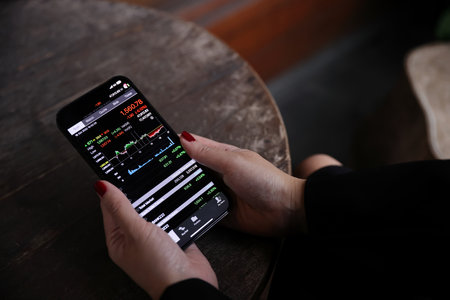 Woman hand using a smartphone for Stock exchange trading online in the coffee shop, business concept