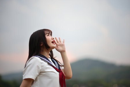Japanese high school student shouting on countryside backgroundの写真素材