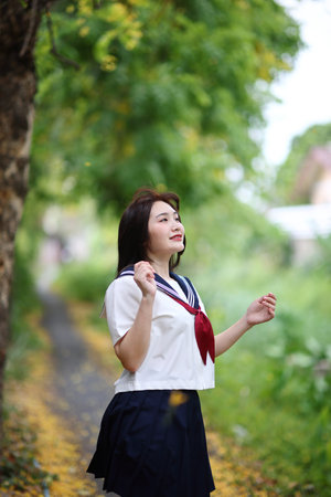Japanese high school student looking in park with tree backgroundの写真素材
