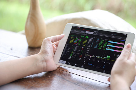 Woman hand using a tablet for Stock exchange trading online in the coffee shop, business conceptの写真素材