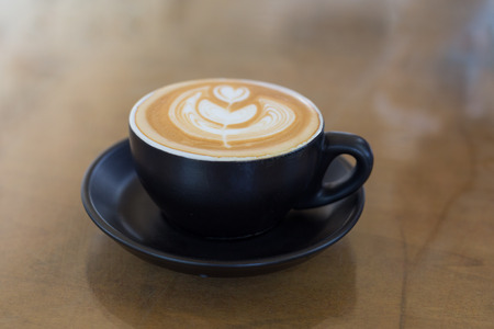 hot latte art coffee in black mugの写真素材