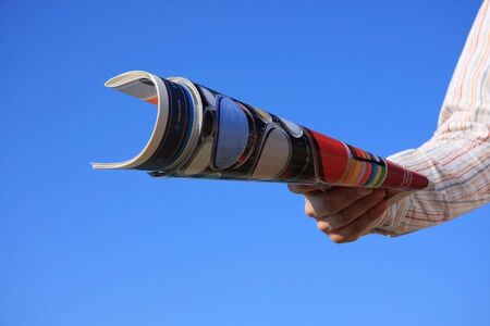 Hand holding a magazine roll isolated on a blue skyの写真素材