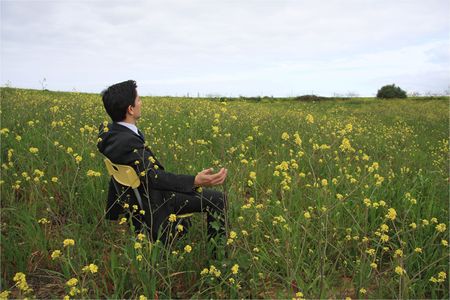 A business man sitting in a field enjoying the natureの写真素材