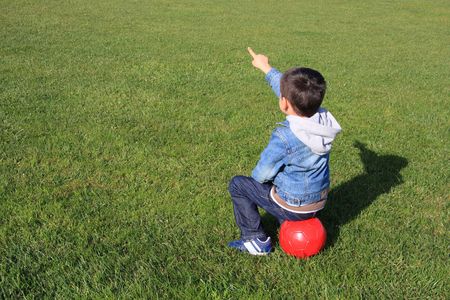 A little boy with a red ball sitting on the gassの写真素材