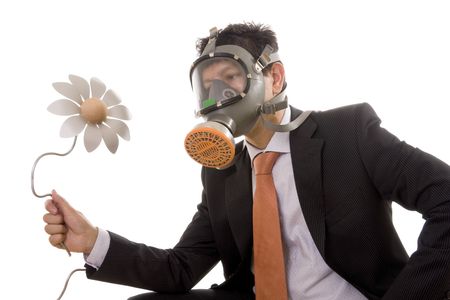 A businessman with a gas mask looking to an artificial flowerの写真素材