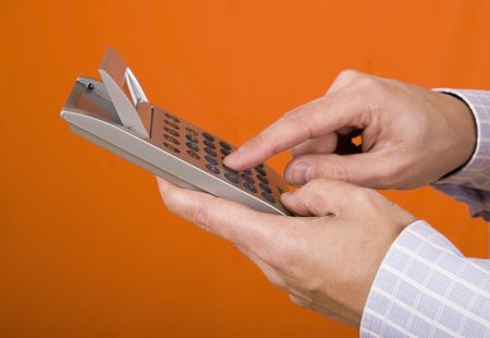 Hand with a calculator isolated on an orange backgroundの写真素材
