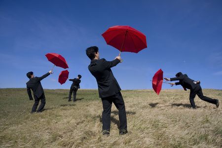 Four businessman with red umbrellas on the natureの写真素材