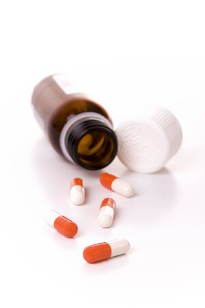 An open container with orange and white capsules - Focus on the first capsuleの写真素材