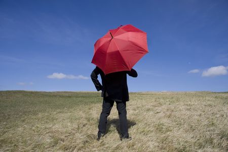Business man with an umbrella on the meadowの写真素材