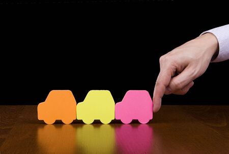 Protection concept - Finger pushing / helping a line of colorful carsの写真素材