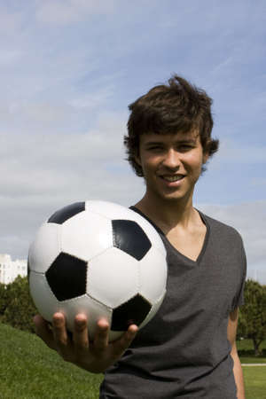 Young man holding a black and white soccer ballの写真素材