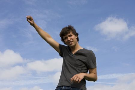 Casual Young man with his arm up on a blue skyの写真素材