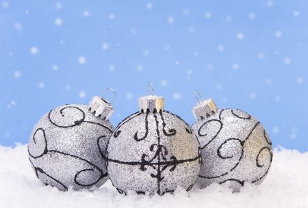 Three silver xmas baubles on a blue backgroundの写真素材