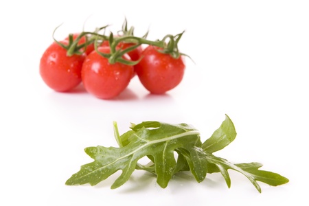 Tomatoes and rucola leaves isolated on white - Focus on the rucolaの写真素材