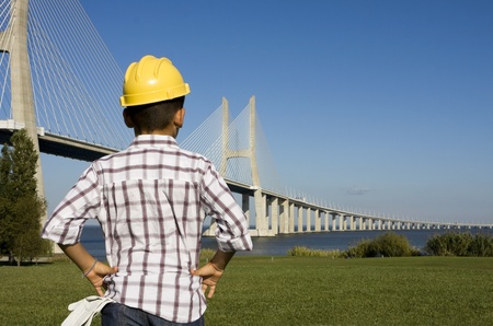 Little boy with gloves and a helmet looking to a bridgeの写真素材