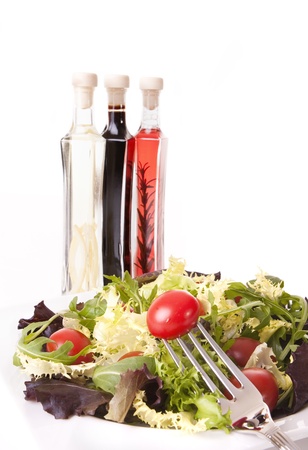 Healthy food concept - Tomatoes and green salad with styled aromatic vinegar bottle on backgroundの写真素材