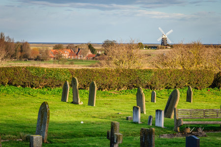 A windmill by the Norfolk UK coast as seen from church graveyardの写真素材