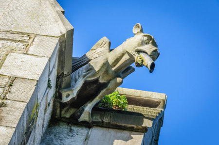 A stone gargoyle on a Welsh church tower on a bright summers dayの写真素材