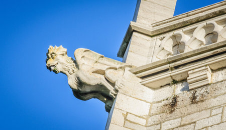 A stone gargoyle on a Welsh church tower on a bright summers dayの写真素材