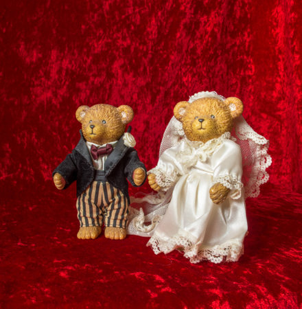 Two toy teddy bears made up as bride and groom on a rich red backgroundの写真素材