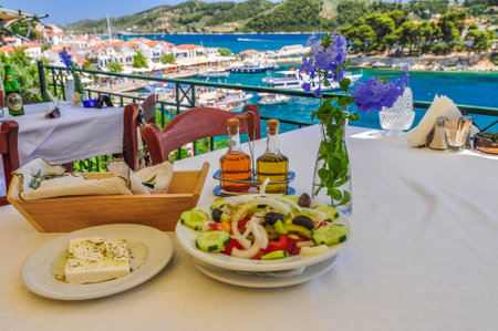 Old Skiathos restaurant, over looking the harbour with boats in a blue sea and a Greek salad waiting to eaten.の写真素材