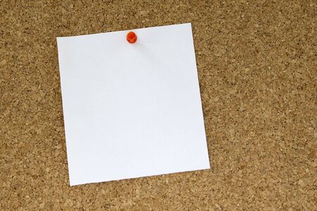 white paper note in cork background with red pinの写真素材