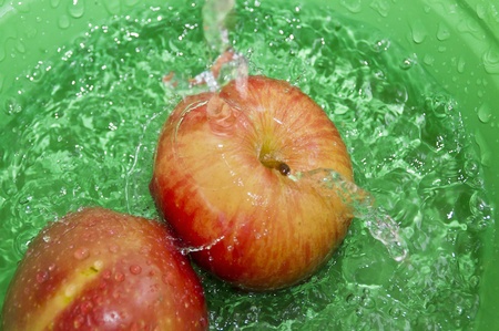 Apples on water splash in green backgroundの写真素材