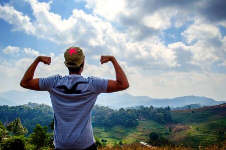 strong man shows his muscle over mountain lanscape の写真素材