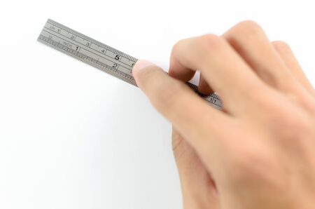 Hand using a ruler to measure on a white backgroundの写真素材