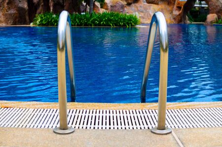 Grab bars ladder in the blue swimming poolの写真素材