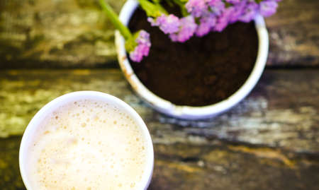 Cup of hot chocolate milk with beautiful flower and coffee ground on vintage wooden background, selective focusの写真素材