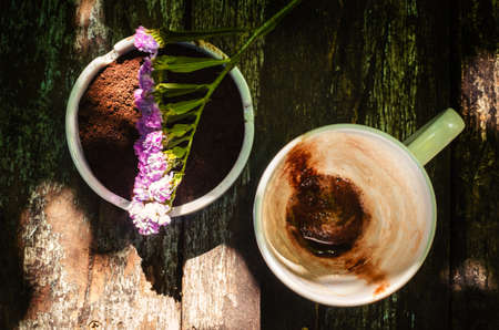 Cup of hot chocolate milk with beautiful flower and coffee ground on vintage wooden background, selective focusの写真素材