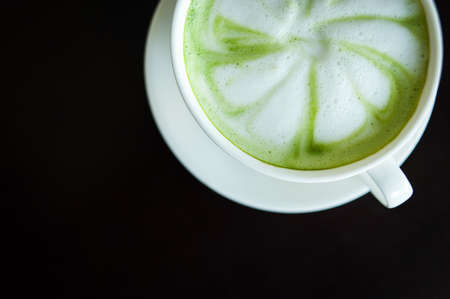 Hot milk green tea (selective focus) in the white cup on the dark wooden table.の写真素材