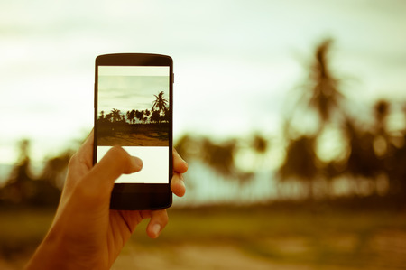 Close-up Hand holding smart phone with blurred nature background - vintage filterの写真素材