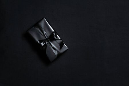 Top view of black gift box with black ribbons isolated on black background. Shopping concept boxing...