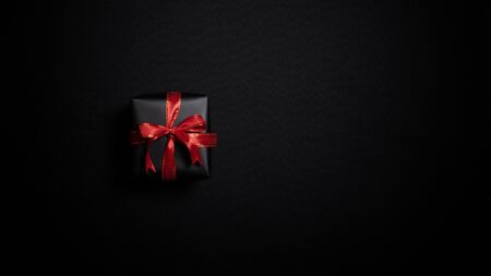 Top view of black gift box with red ribbons isolated on black background. Shopping concept boxing day and black Friday sale composition.の写真素材