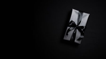 Top view of black gift box with black ribbons isolated on black background. Shopping concept boxing day and black Friday sale composition.の写真素材