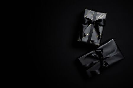 Top view of black gift box with black ribbons isolated on black background. Shopping concept boxing day and black Friday sale composition.の写真素材