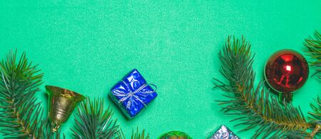 The concept of the new year, christmas. Top view of Christmas gift box red balls with spruce branches and bell on green background.の写真素材