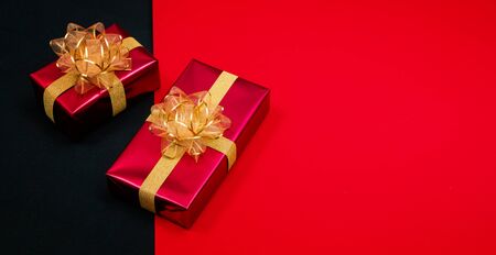 Top view of black gift box with red and black ribbons isolated on red and black background. Shopping...