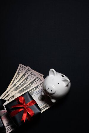 Top view of gift box with red, black ribbons, money and piggy bank isolated on black background. Shopping concept boxing day and black Friday sale composition.の写真素材