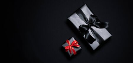Top view of gift box with red and black ribbons isolated on black background. Shopping concept boxing day and black Friday sale composition.の写真素材