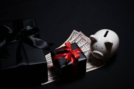 Top view of gift box with red, black ribbons, money and piggy bank isolated on black background. Shopping concept boxing day and black Friday sale composition.の写真素材