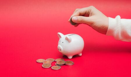 Close up shot of woman hand putting money coin into piggy. Save money and financial investment concept with copy space, banner.の写真素材