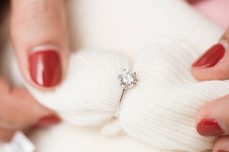 Close up of an elegant engagement diamond ring on woman finger with pink sweater winter clothe. love, wedding and Valentine's day concept.の写真素材