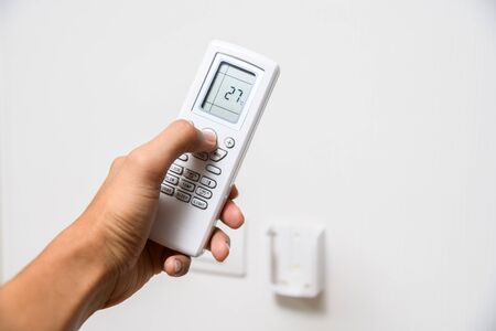 Hand with remote control directed on air conditionerの写真素材