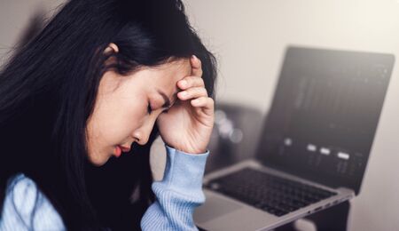 An asian woman getting anxiety and depression after checking stock market news about global pandemic. Lockdown mental health. Coronavirus outbreakの写真素材