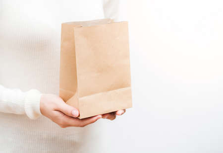 Close up shot of female hands holding a small gift wrapped with gold ribbon. Shallow depth of field with focus on the little box.の写真素材