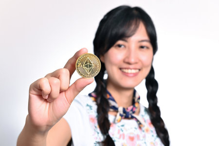 Young asian woman holding a gold bitcoin coin on white background.の写真素材